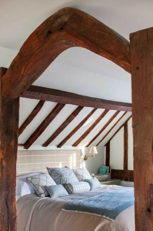 спальня с дубовым каркасом с балками и пуховым одеялом