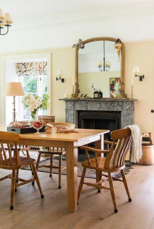 дървена маса за хранене и столове в кремава трапезария с камина и огледало