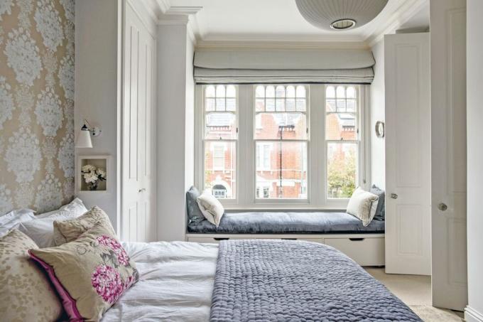 светлая и большая главная кровать с декоративной стеной и сиденьем у окна, сфотографированная Polly Eltes