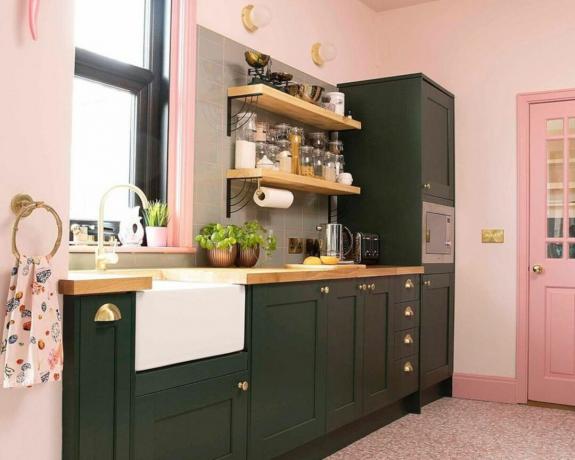 kaksisävyinen kontrastivärinen keittiö, jossa vaaleanpunaiset seinät ja mustat kaapit