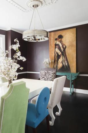 salle à manger marron chocolat avec cimaise, oeuvre d'art, table à manger blanche, suspension, chaises dépareillées