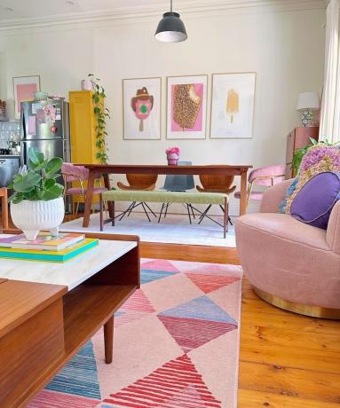 Un piccolo soggiorno con tappeto, sedie, tavolo da pranzo e quadri alle pareti