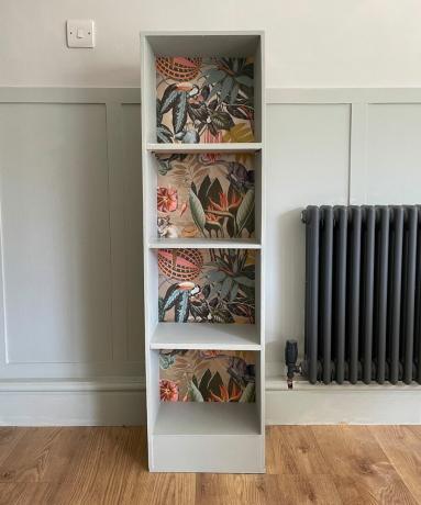 Drvena polica za knjige obojena u blijedozelenu boju sa stražnjim pločama od tapeta