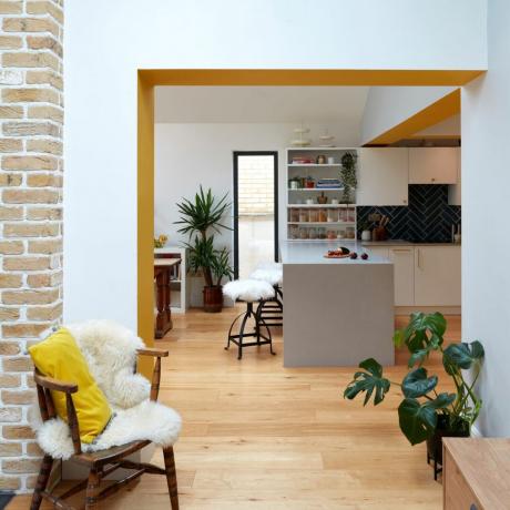 Aufnahme in die Küche mit weißer Arbeitsplatte und gelb lackierter Unterseite bis zum Türrahmen