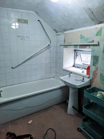 Før skud viser badeværelse med brunt tæppe, almindelige hvide vægfliser og badekar-bruser