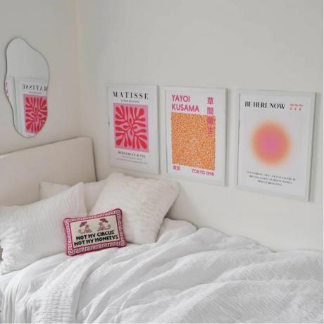 Tres carteles rosas y naranjas en paredes blancas.
