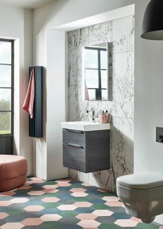 洗面器ユニット、バスルームミラー、緑、ピンク、グレーの六角形の床タイルを示すバスルーム
