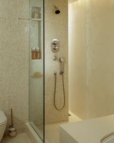 tessere di mosaico color crema nel bagno con doccia con piastrelle color crema più grandi su parete e pavimento, parete di vetro