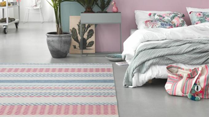 Schlafzimmer mit Wänden in Pastelltönen und bunt gemustertem Teppich auf dem Boden