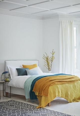Бяла спалня с цветни възглавници