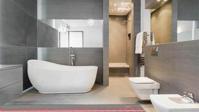 Valkoinen ja harmaa ylellinen kylpyhuone -sviitti, jossa on kylpyamme, suihku, peili ja lattialämmitys