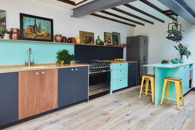 cozinha sem puxadores com armários em madeira, turquesa e preto com bancos amarelos e piso de madeira