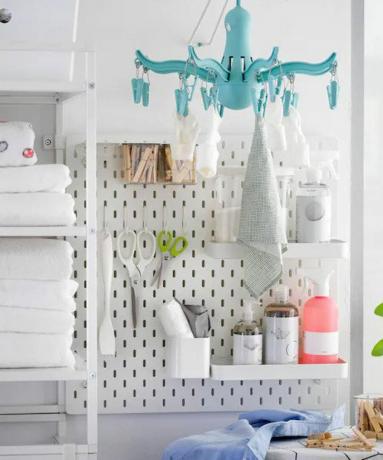 ophangbord met planken in een kleine wasruimte met blauwe wasdroger, planken en strijkplank