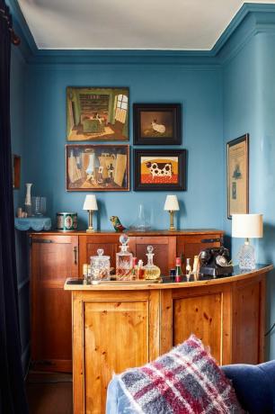 sininen olohuone, jossa puinen baarikärry, maalauksia ja puinen senkki