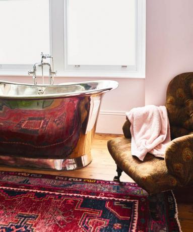 Рефлективна тенекиена вана с пурпурно-розов шарен килим и кафяв фотьойл с щампа на паун