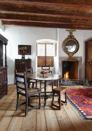confortável com mesa de jantar e lareira acesa em casa do século 17
