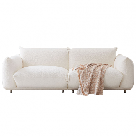 Un canapé bouclé blanc avec des coussins et une couverture neutre