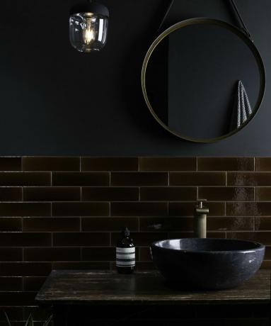 Melnā un tumši brūnā vannas istaba ar spīdīgām flīzēm no oriģinālā stila
