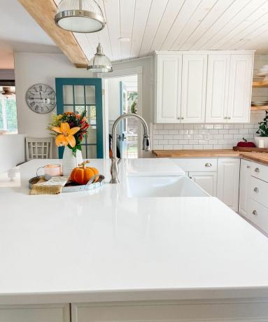 Hvit kjøkkenbenk med sølvdetaljer og pendelbelysning i glass