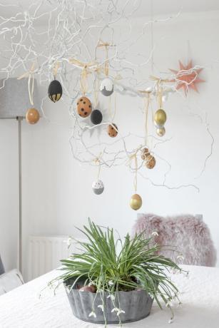 sufragerie cu crengi de copac de Paște atârnând cu decorațiuni de ouă de Paște