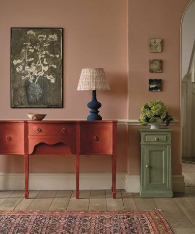 Ružičasto predsoblje s crvenim konzolnim stolom i cvjetnim zidnim umjetninama