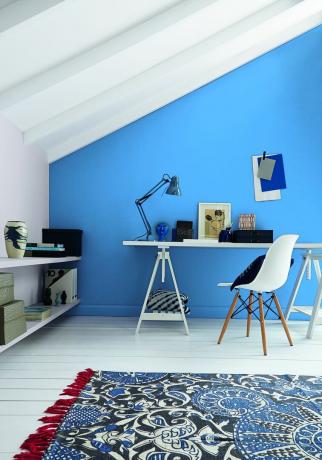 Birou de acasă în mansardă cu perete albastru, podea albă, birou și scaun alb