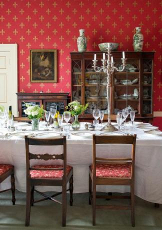 salle à manger avec table dressée, chandelier et murs rouges