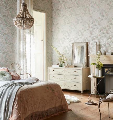 Camera da letto romantica con cassapanca vintage bianca, lino delicato e carta da parati a motivi bianchi