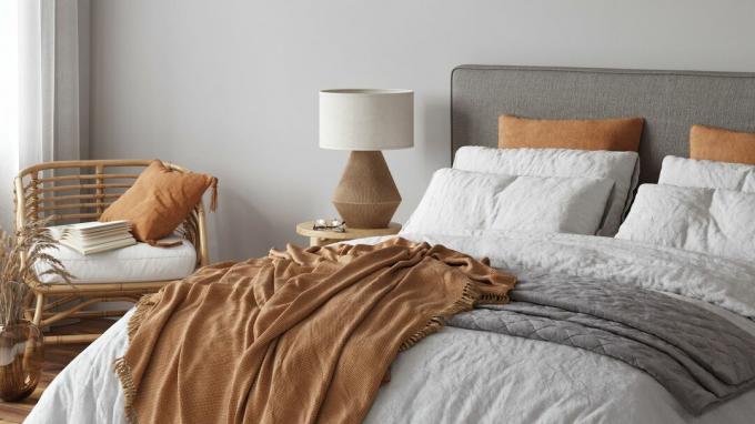 camera da letto minimalista grigia e arancione con letto, comodino e sedia