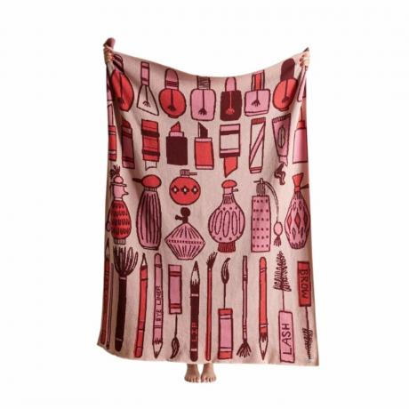 Asmuo, laikantis rožinę antklodę su makiažo iliustracijomis