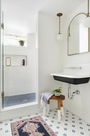 bagno bianco con lavabo vintage, specchio retrò e applique, sgabello, cabina doccia e tappeto vintage