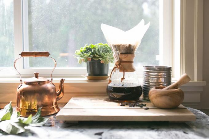 hæld kaffe over på køkkenbordet med sukkulenter og bronze te-kedel
