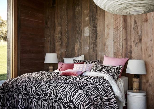 シマウマの寝具のクッションが付いている木製の羽目板の羽目板が付いている寝室の内部