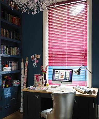 Greznas rozā žalūzijas tumši zilā mājas birojā ar koka galdu un sudraba krāsas polsterējumu