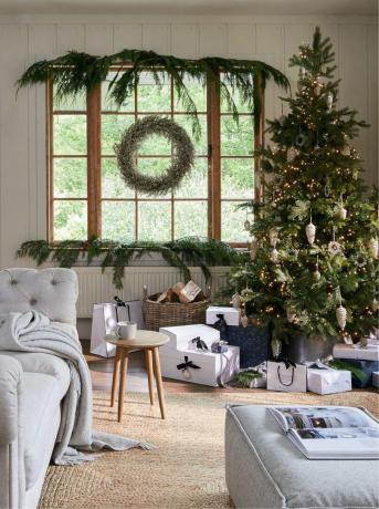 Tampilan jendela Natal: karangan bunga di jendela dengan karangan bunga di ambang jendela