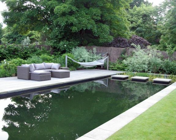 O piscină verde cu terasă și hamac
