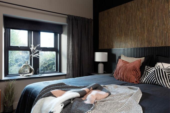 Dormitorio de invitados con cabecero de paneles negros extendidos y papel tapiz marrón efecto pluma