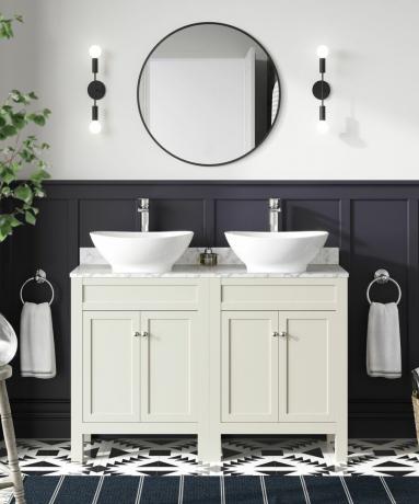 monokromatiskt badrum med dubbelt handfat och en stor rund spegel