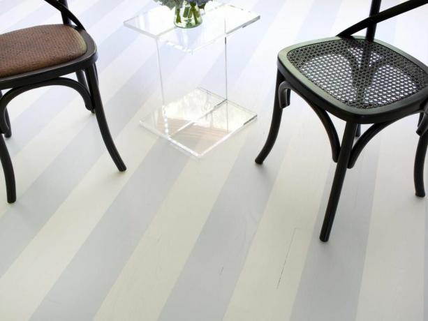 Широкие полосы на деревянном полу окрашены в мягкий серый и белый цвета.