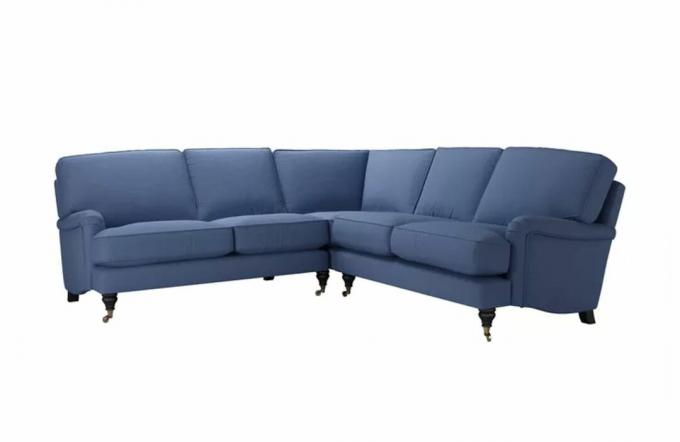 Классический угловой диван с точеными деревянными ножками на колесиках и темно-синей льняной обивкой.