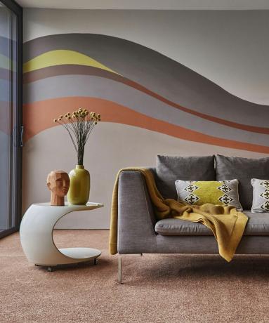 Kūrybingų dažų idėja ant sienos su šluojančiais atspalviais pilkais, geltonais ir terakotos atspalviais.