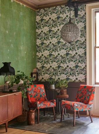 Σαλόνι με πράσινους τοίχους και τοίχο με εκτύπωση μοτίβου ζέβρας,. Δύο κόκκινες πολυθρόνες κάθονται μπροστά στον τοίχο.