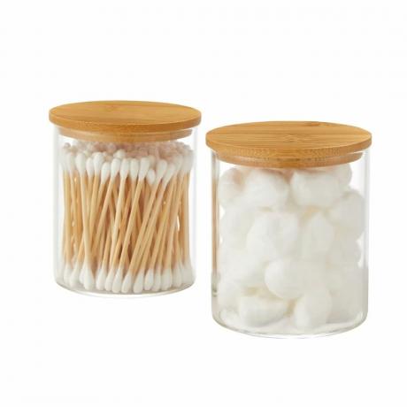 Dois frascos de vidro com tampas de bambu contendo cotonetes e bolas de algodão