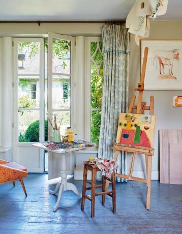 Taiteilijan maalausteline lähellä ranskalaista ikkunaa maalaistalon keittiössä