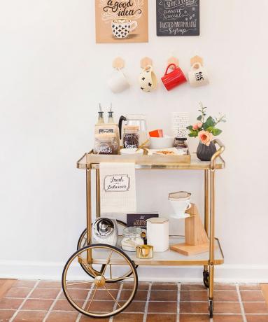 Glam DIY візок для кав’ярні з золотистим покриттям, стилізований персоналізованими кольорами, квітами та доповнений підвісними кухлями на стіні та принтами, наклеєними на стрічку Washi