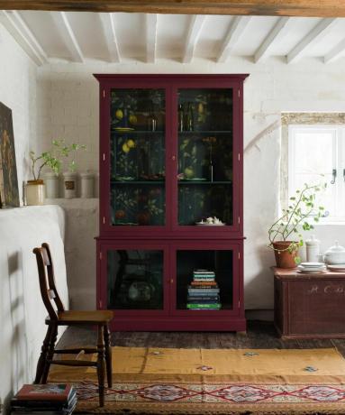 Une armoire de cuisine rouge avec des détails à motifs noirs et floraux à l'intérieur