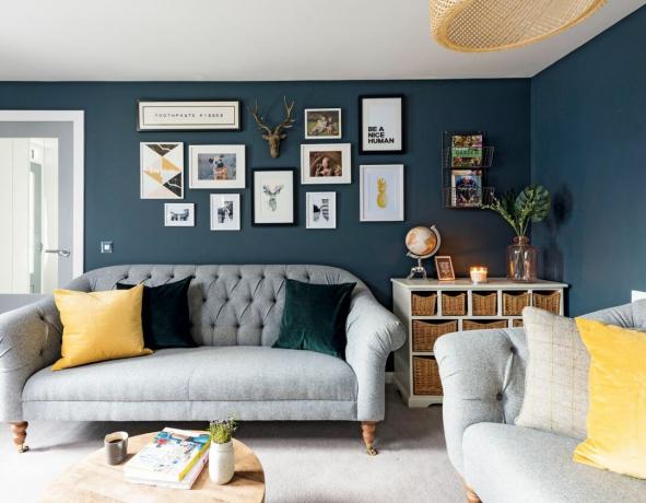 Un soggiorno blu scuro con accenti gialli e un divano grigio