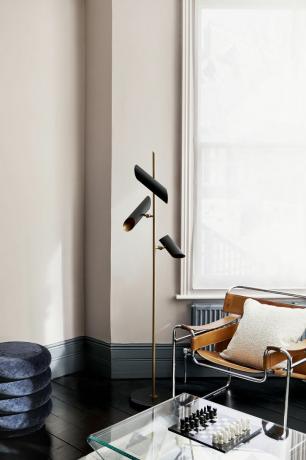 schema beige e antracite con lampada da terra nera, sedia in pelle marrone chiaro, pavimento verniciato nero, tavolino in vetro
