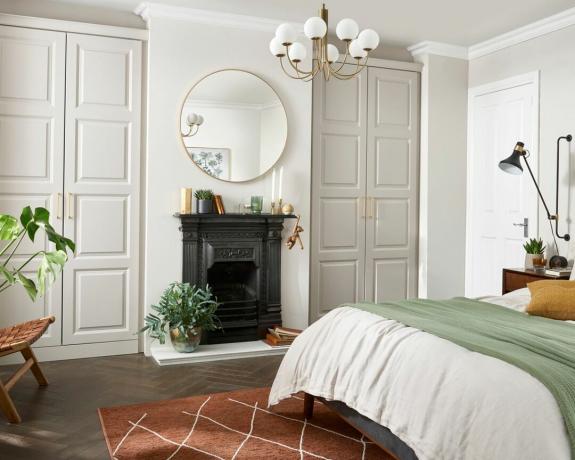 Un dulap principal alb într-un dormitor cu un șemineu tradițional