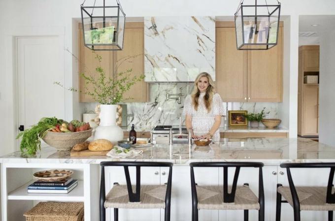 Komplette Rückwand aus Marmorplatten in einer modernen Küche mit weißer Kochinsel und dunkler Sitzumrandung für Hochstühle